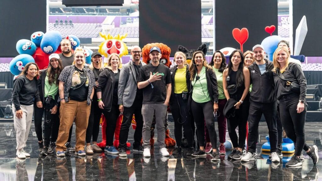 The emc3 team posing with colorful cartoon mascots behind them