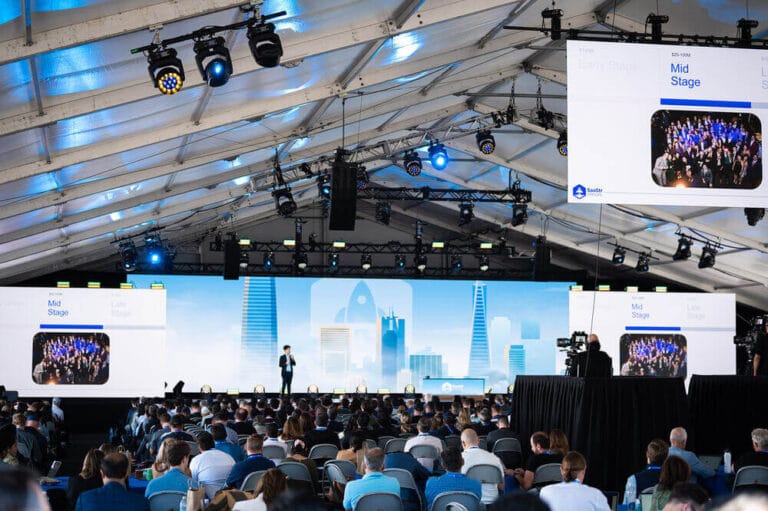 Conference with large audience and keynote speaker under a grand tent